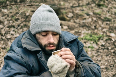 Poor homeless man with cup in city park