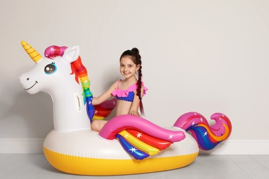 Photo of Cute little girl on bright inflatable ring near light wall