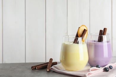 Photo of Glasses with delicious milk shakes on table. Space for text