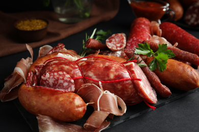 Photo of Different types of sausages served on black table, closeup