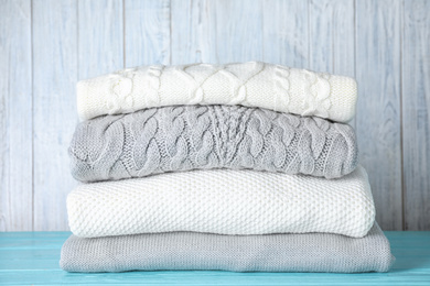 Image of Stack of folded warm sweaters on turquoise wooden table