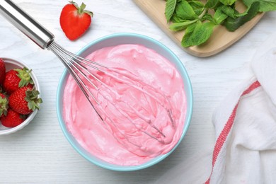 Photo of Strawberry cream with balloon whisk on white wooden table, flat lay