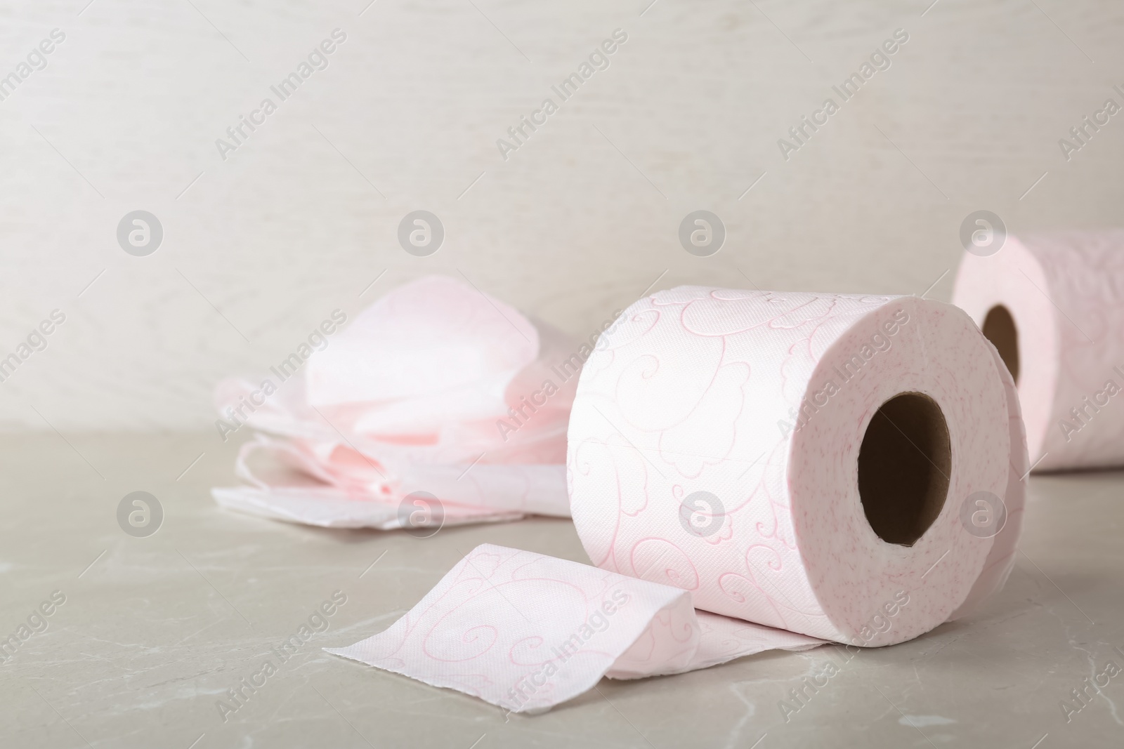 Photo of Roll of toilet paper on grey table. Space for text