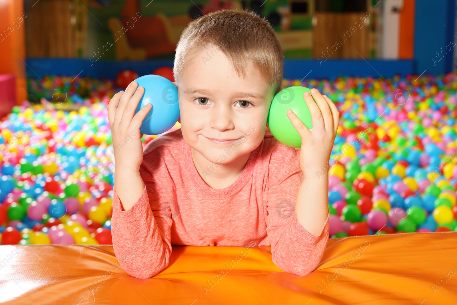 Photo of Cute child playing in ball pit indoors