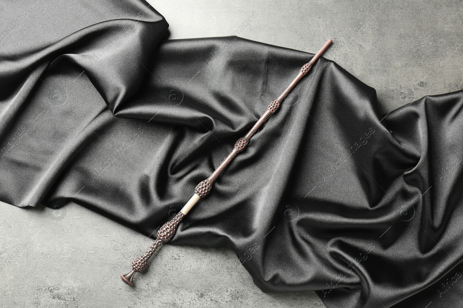 Photo of Magic wand and dark cloth on light grey background, top view