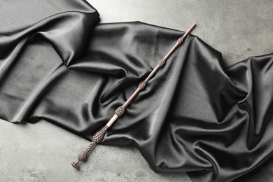 Magic wand and dark cloth on light grey background, top view