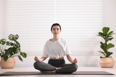 Photo of Beautiful girl meditating on mat in yoga studio