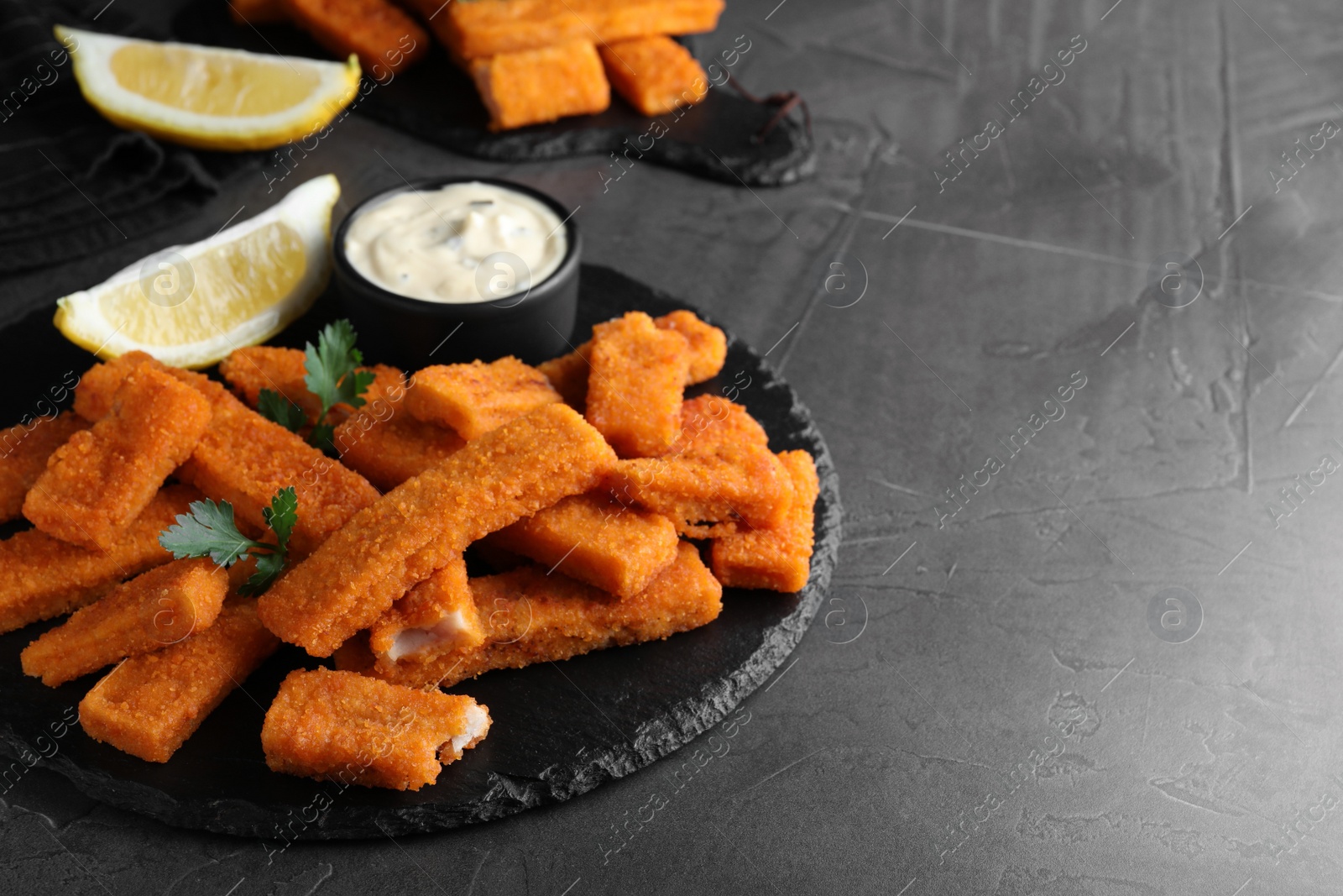 Photo of Tasty fresh fish fingers served on black table, space for text