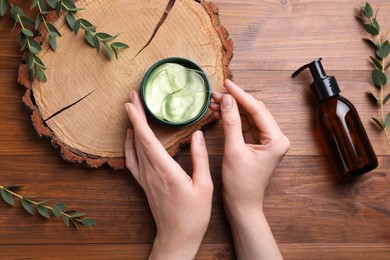 Photo of Woman with package of under eye patches at wooden table, top view. Cosmetic product