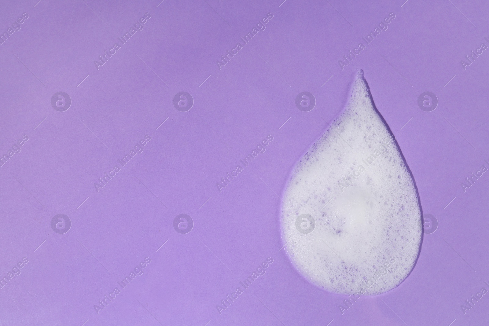 Photo of Sample of cleansing foam on violet background, top view with space for text. Cosmetic product