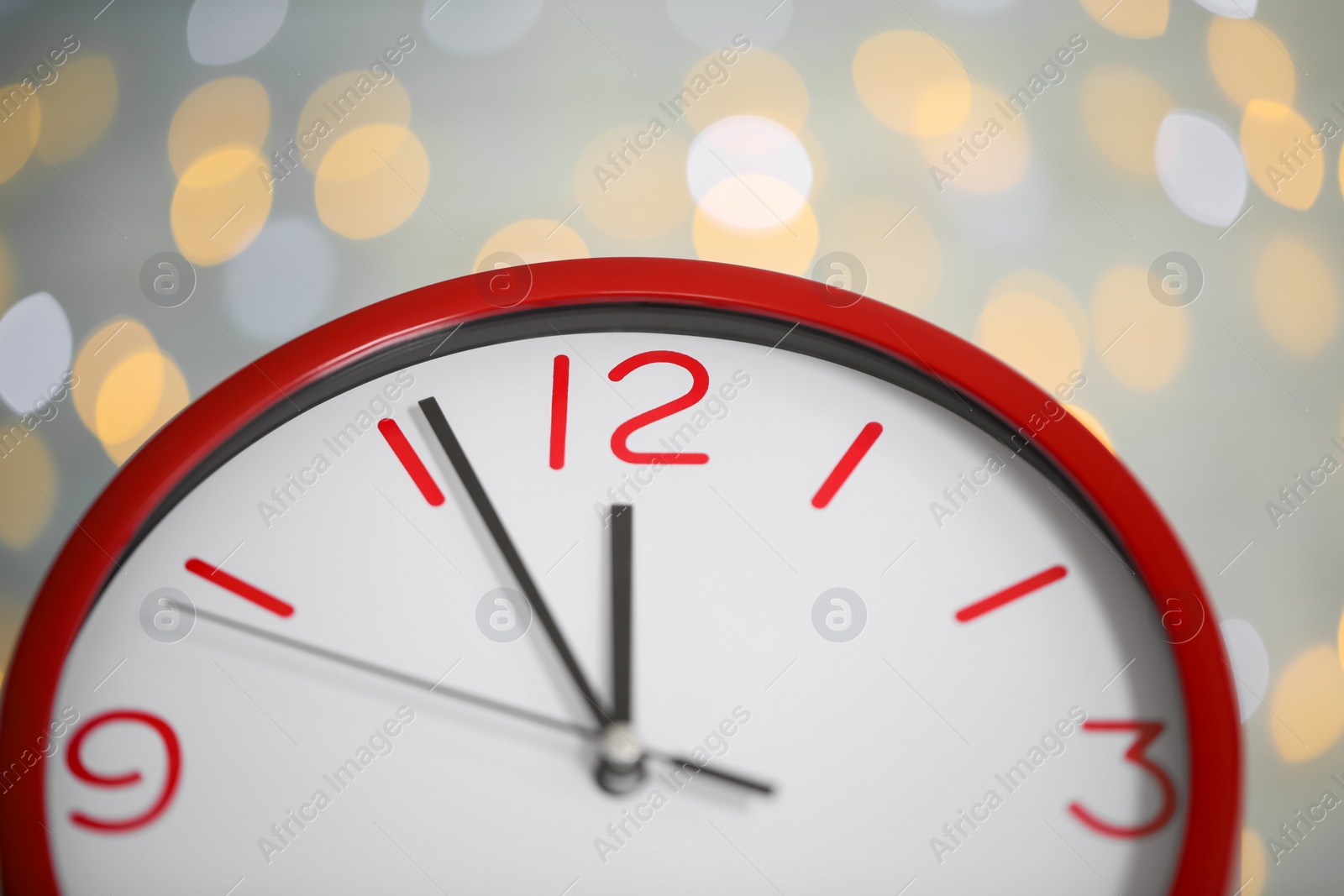 Photo of Clock showing five minutes until midnight on blurred background, closeup. New Year countdown