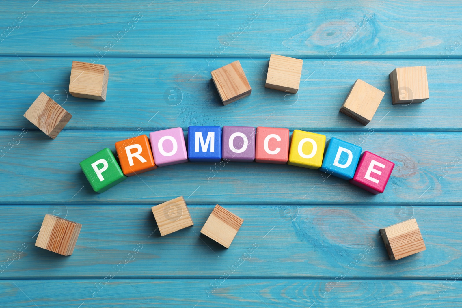 Photo of Word Promocode made of colorful cubes with letters on light blue wooden table, flat lay