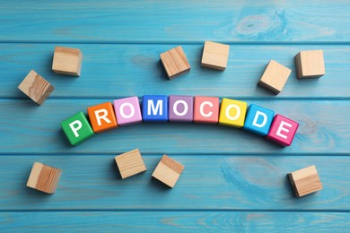 Word Promocode made of colorful cubes with letters on light blue wooden table, flat lay