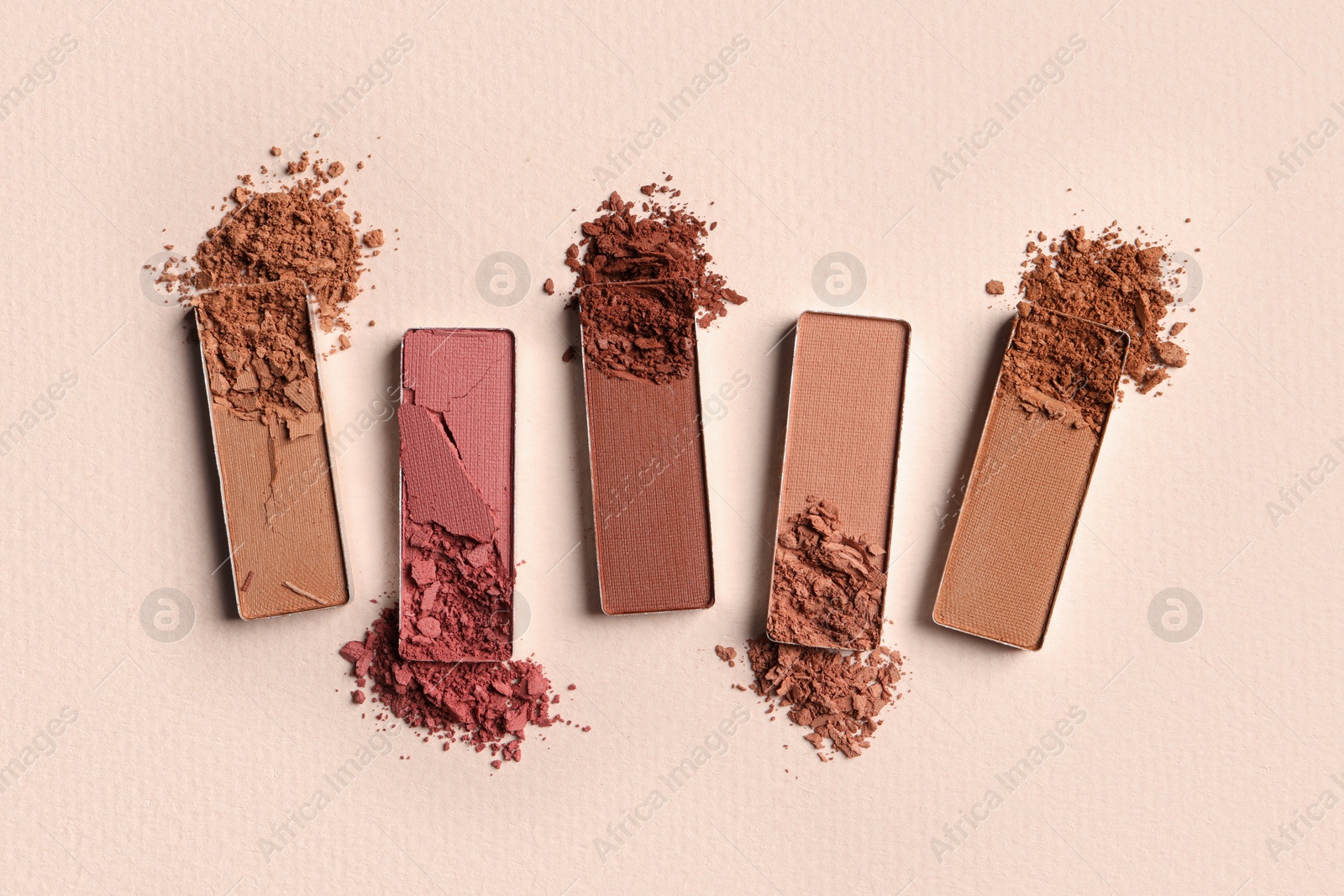 Photo of Different crushed eye shadows on beige background, flat lay