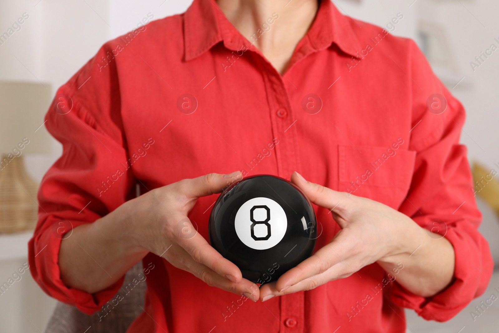 Photo of Woman holding magic eight ball indoors, closeup