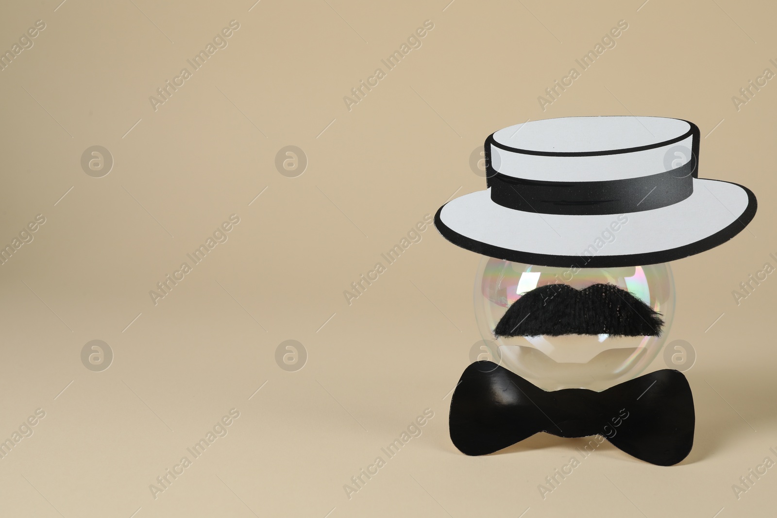 Photo of Man's face made of fake mustache, ball, hat and bow tie on beige background. Space for text