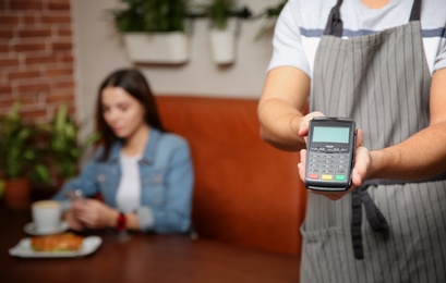 Photo of Waiter with payment terminal in cafe, closeup. Space for text