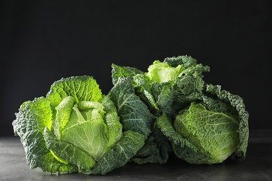 Photo of Fresh green savoy cabbages on grey table against black background