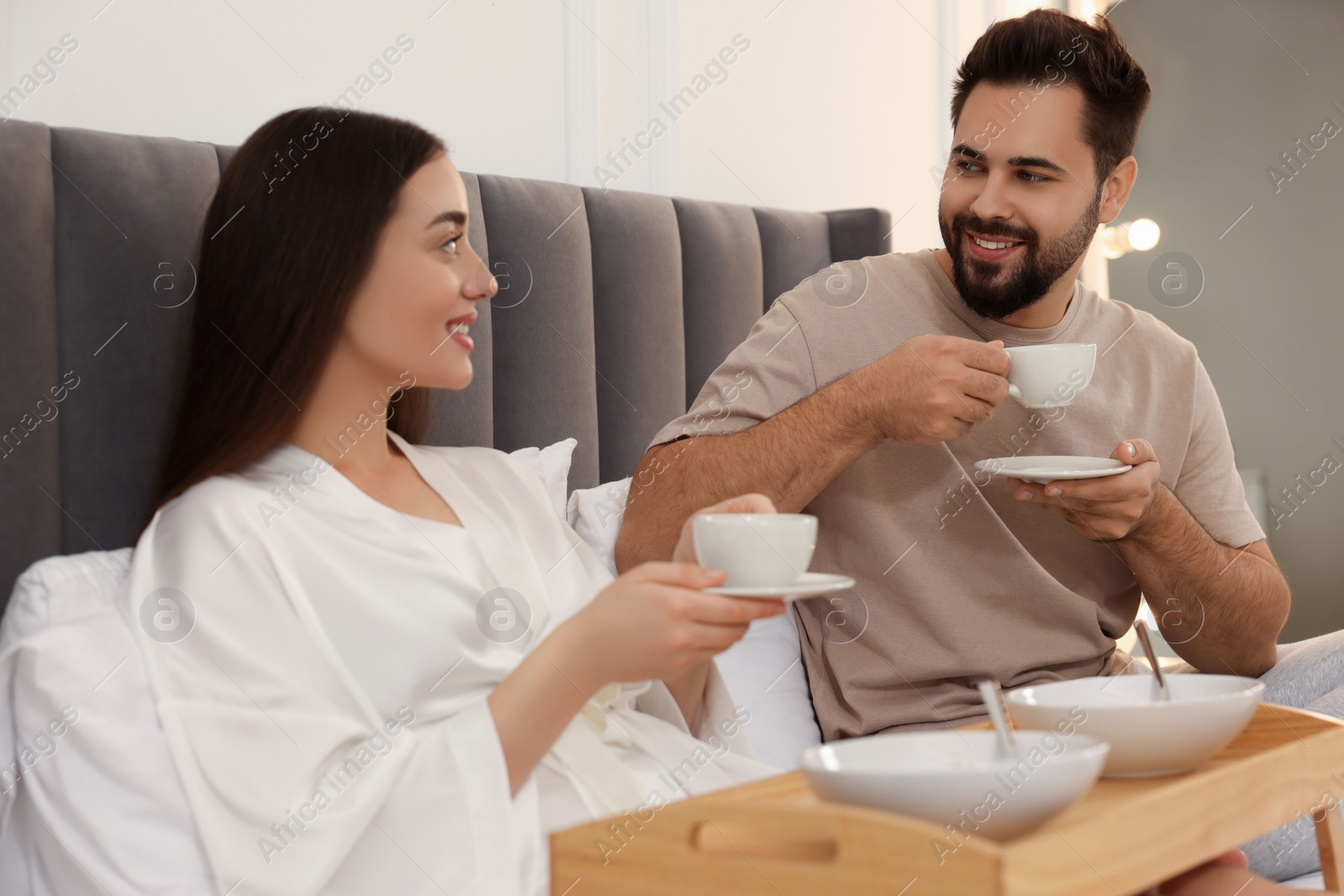 Photo of Happy couple having breakfast on bed at home