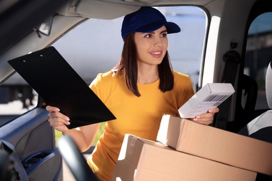 Photo of Courier with clipboard checking packages in car