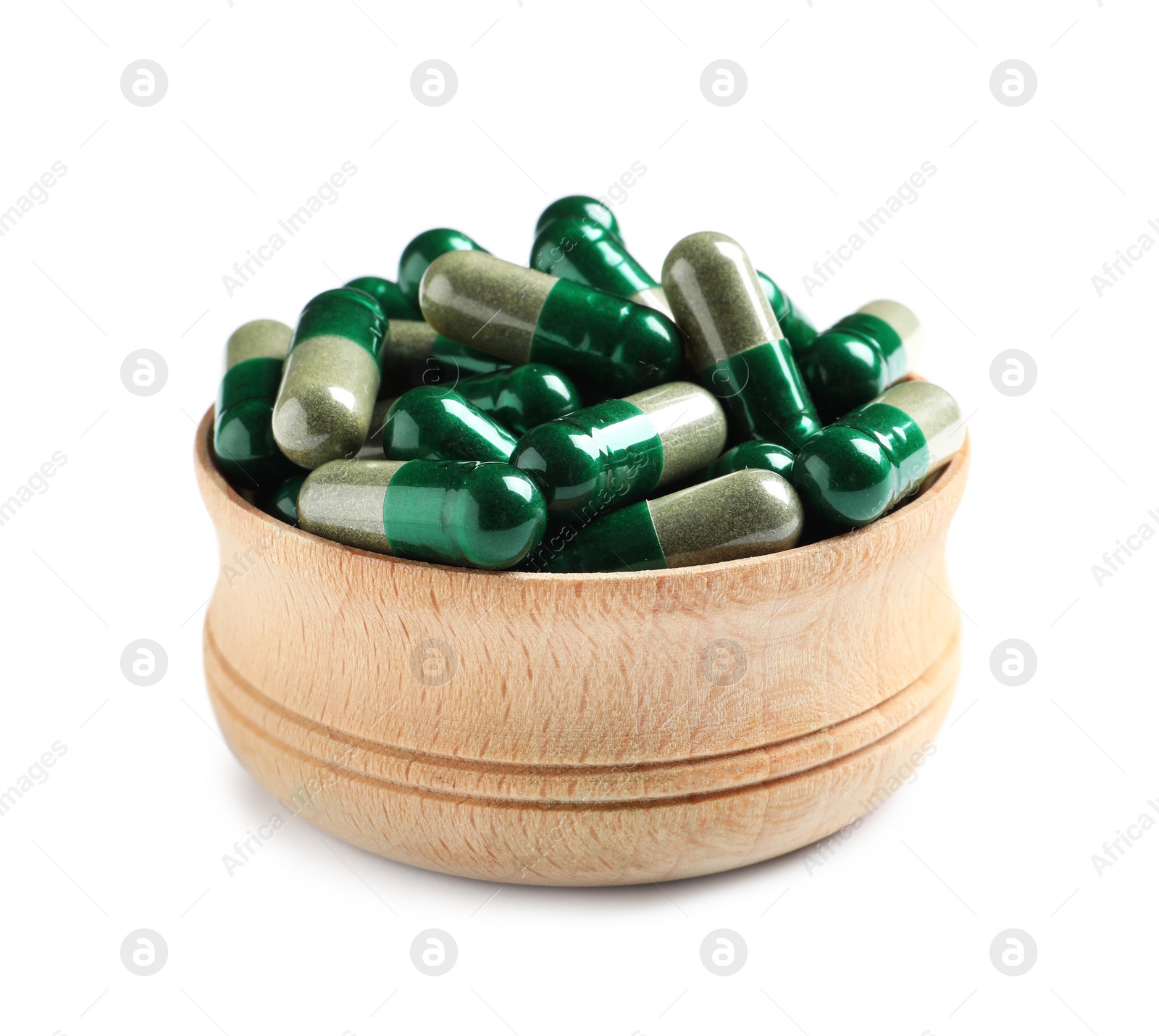 Photo of Wooden bowl with green spirulina capsules on white background