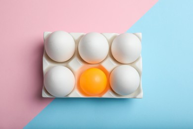 Photo of White eggs and yellow ball in box on color background, top view