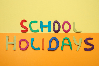 Photo of Phrase School Holidays made of modeling clay on color background, top view