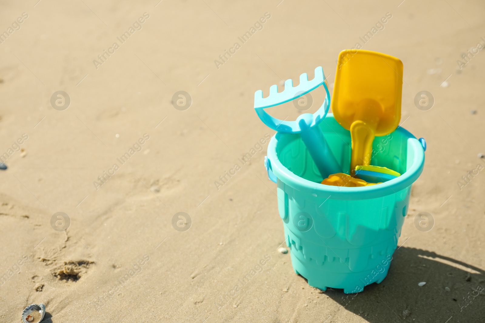 Photo of Different child plastic toys on sandy beach. Space for text