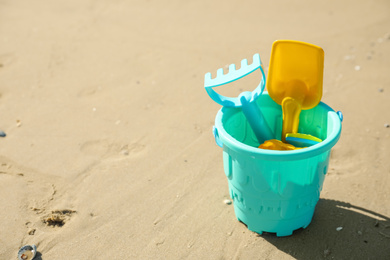 Different child plastic toys on sandy beach. Space for text