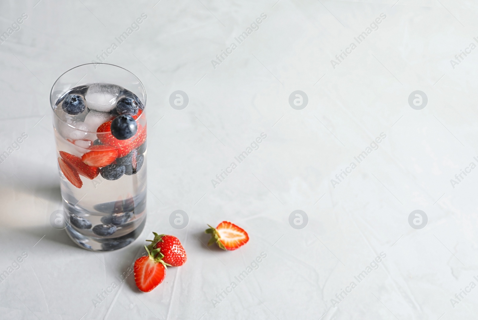 Photo of Natural lemonade with berries in glass on light background