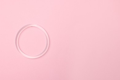 Photo of Diaphragm vaginal contraceptive ring on pink background, top view. Space for text