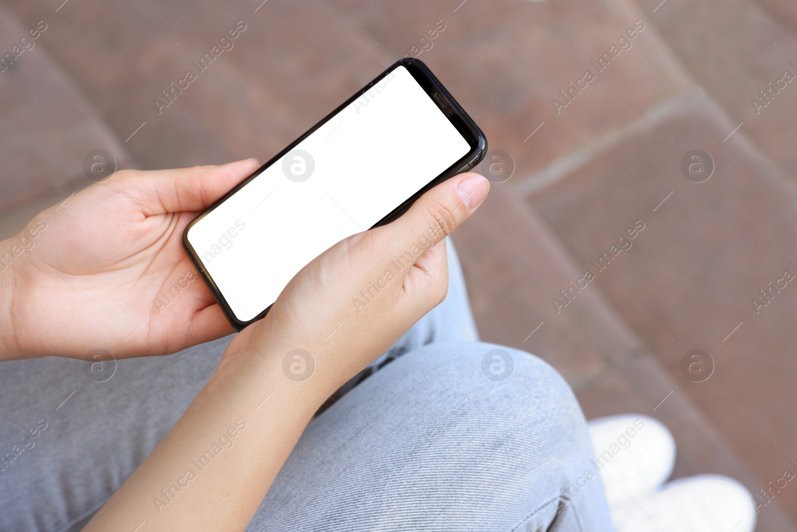 Photo of Closeup view of woman with smartphone sitting outdoors
