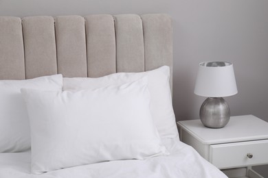 Photo of White soft pillows on bed and lamp in room