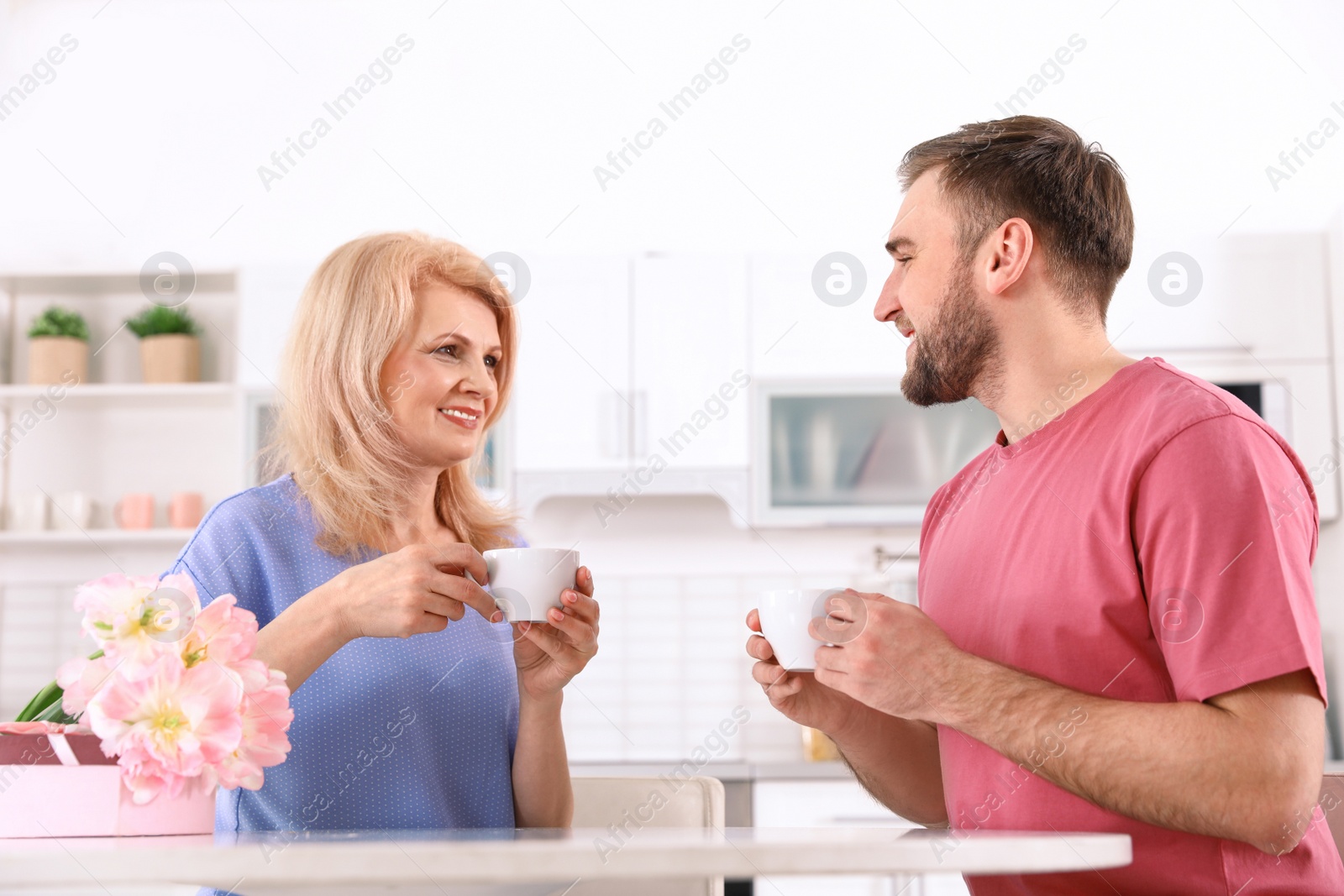 Photo of Young man and his mature mom having breakfast in kitchen. Happy Mother's Day