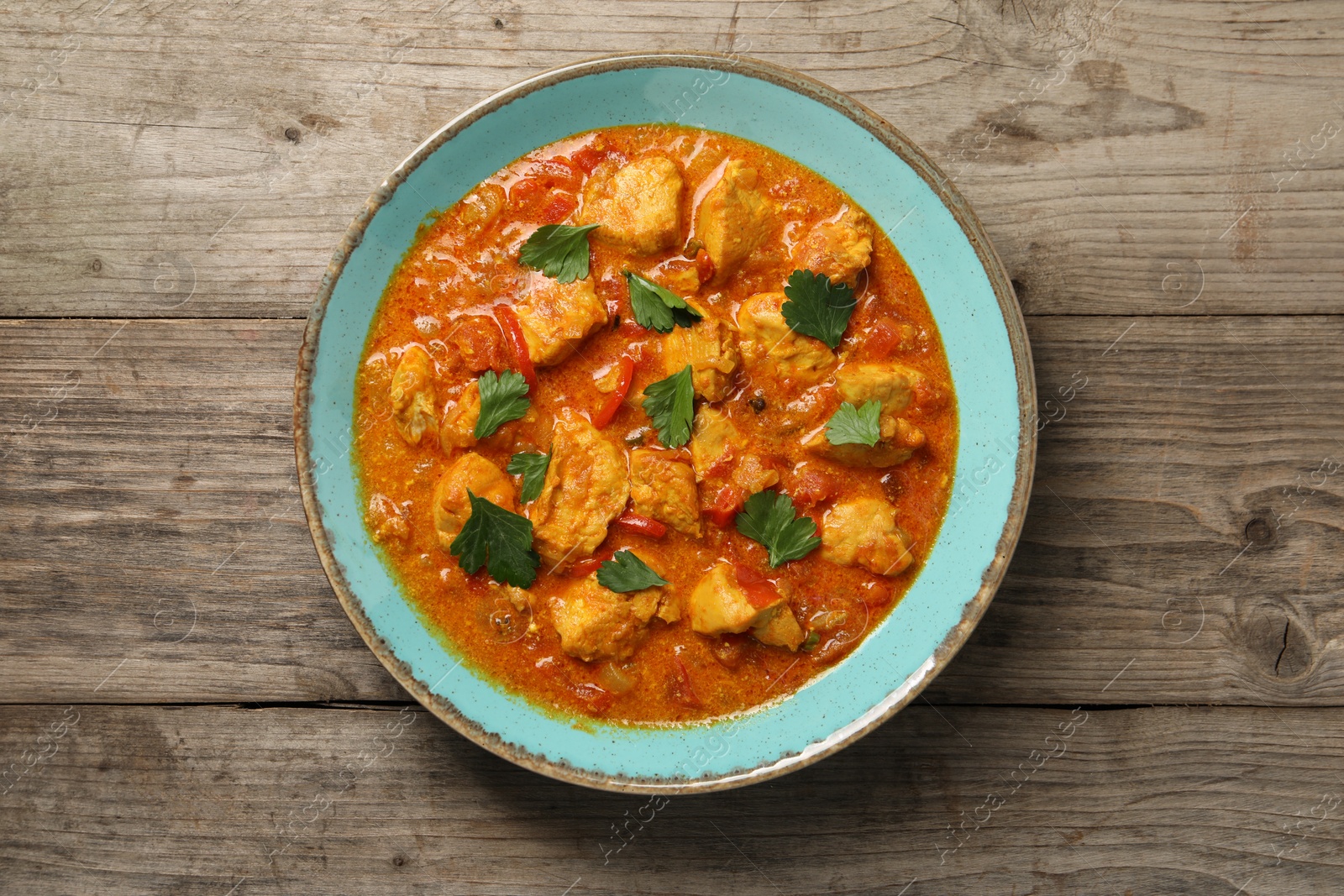 Photo of Delicious chicken curry on wooden table, top view