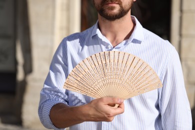 Photo of Man with hand fan outdoors, closeup view