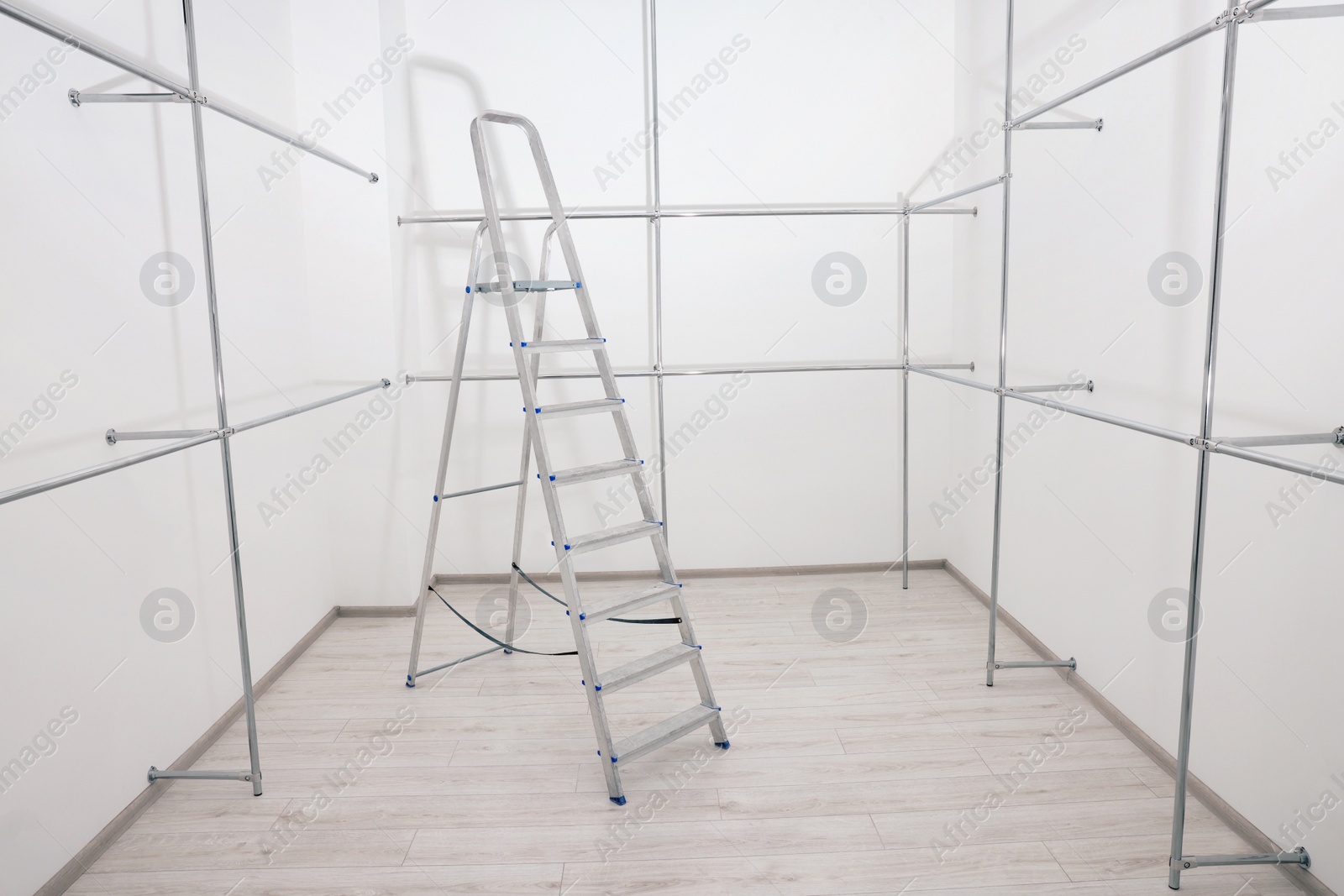 Photo of Ladder and metal pipes in empty renovated room