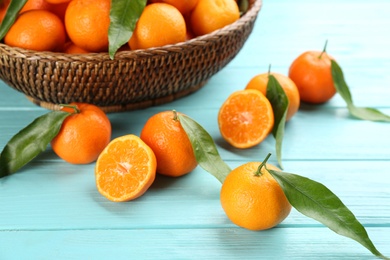 Photo of Fresh tangerines with green leaves on light blue wooden table