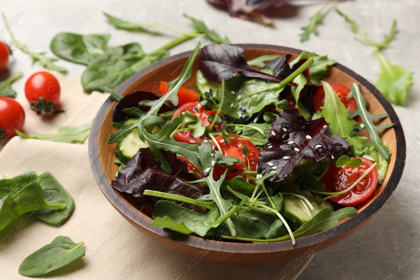 Photo of Tasty fresh vegetarian salad and ingredients on grey table, closeup