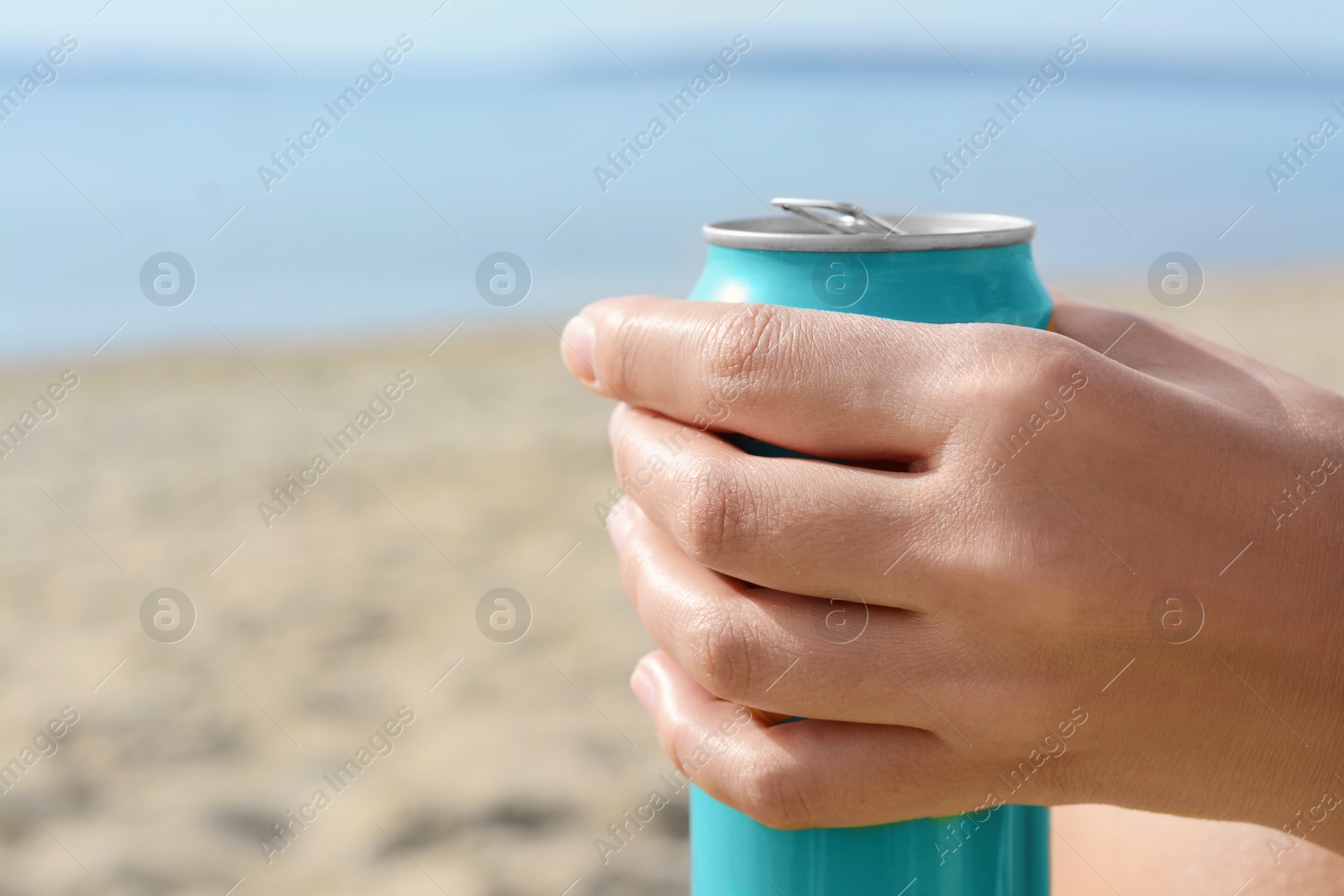 Photo of Woman holding aluminum can with beverage on beach, closeup. Space for text