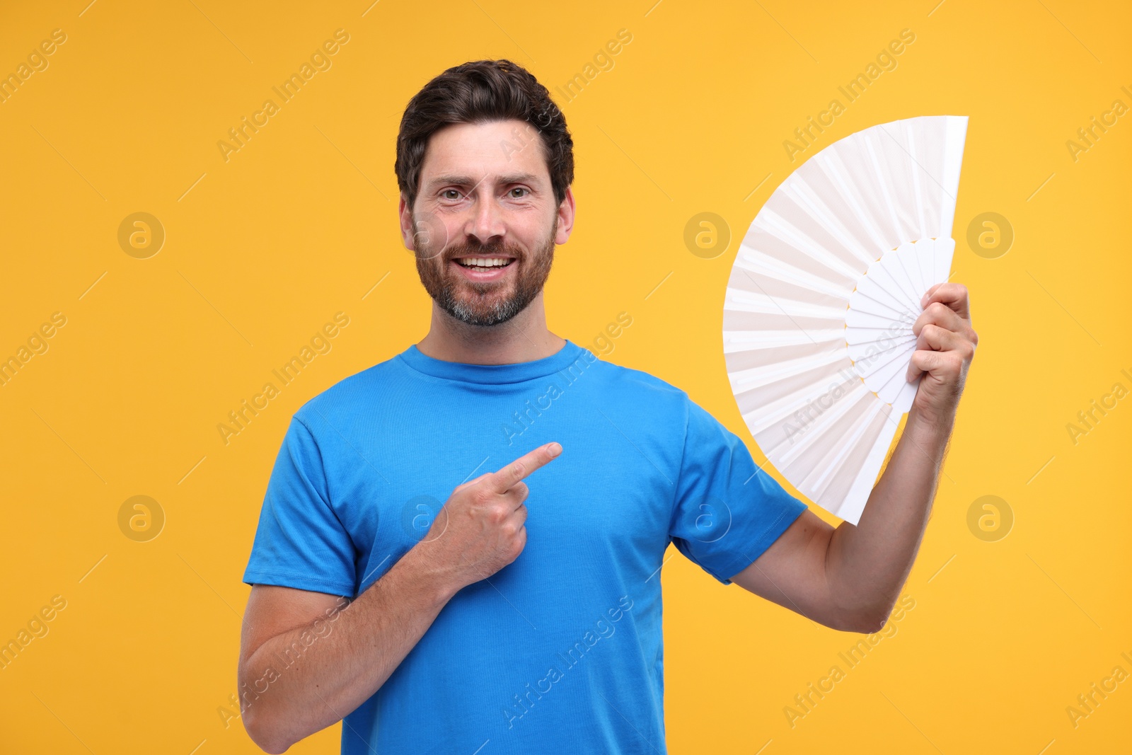 Photo of Happy man holding hand fan on orange background