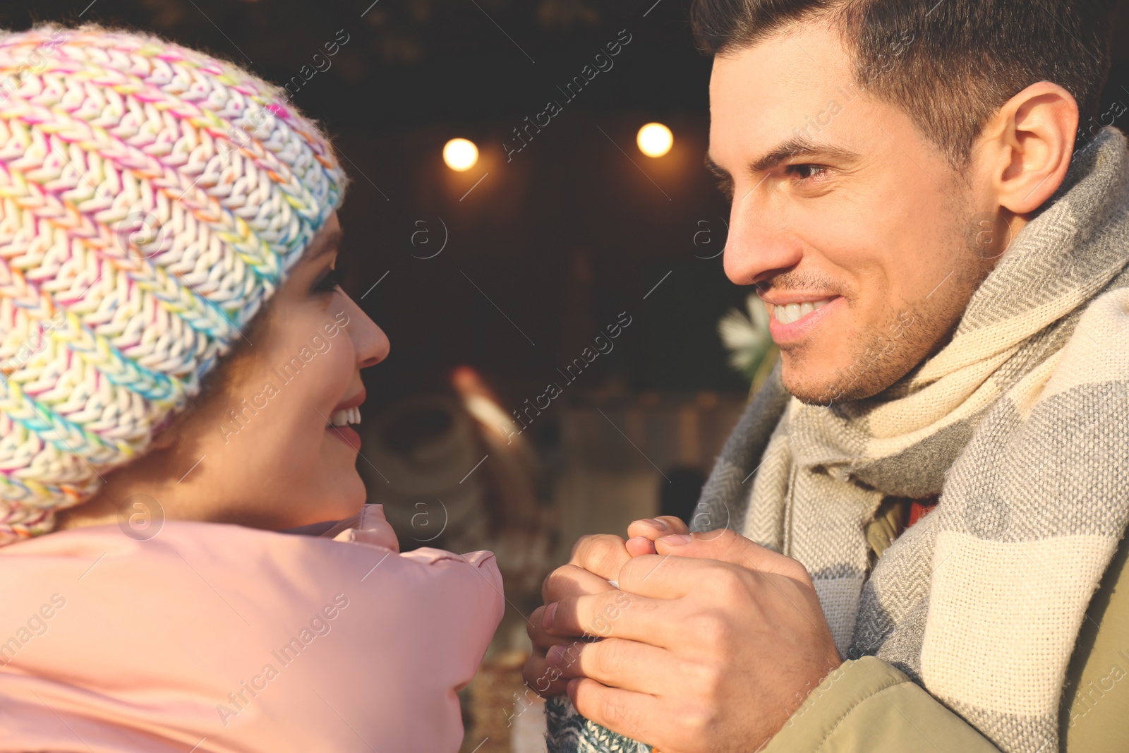 Photo of Happy couple in warm clothes at winter fair. Christmas season