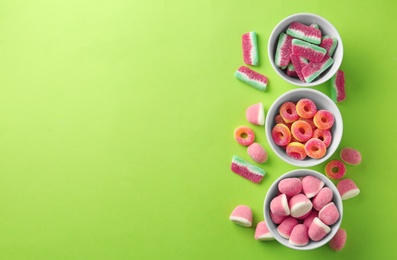 Photo of Flat lay composition with bowls of different jelly candies on green background. Space for text