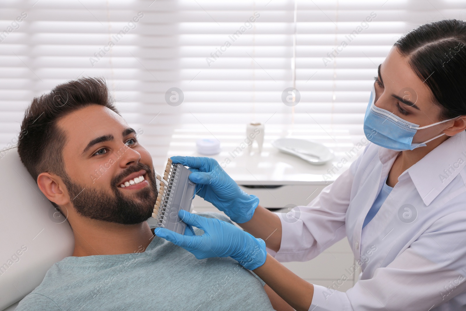 Photo of Dentist checking young man's teeth color in clinic