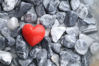 Photo of Red decorative heart on stones and water, top view. Space for text