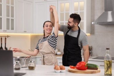 Photo of Happy lovely couple dancing together while cooking in kitchen