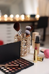 Photo of Different cosmetic products on white table in makeup room