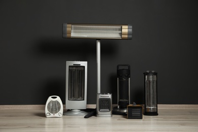 Photo of Set of different modern electric heaters near black wall