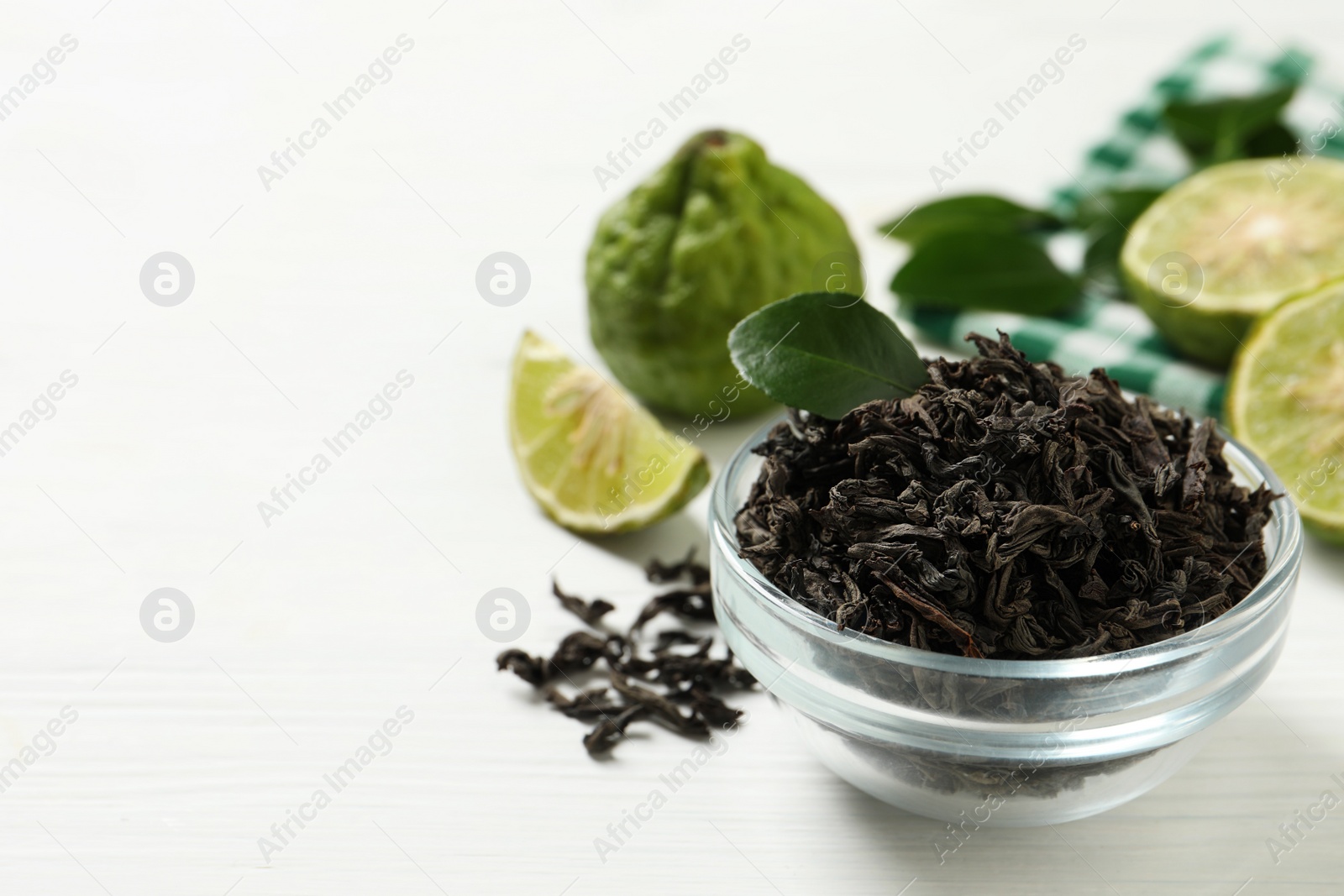 Photo of Dry bergamot tea leaves and fresh fruits on white wooden table, space for text