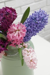 Photo of Beautiful hyacinths in metal can on table, closeup. Spring flowers